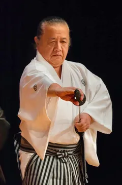 Sōke Hayabuchi drawing a katana while wearing white keikogi and striped hakama